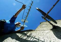 man fixing aerial next to satalite